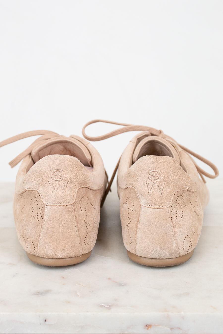 Pair of beige suede shoes on a light marble surface