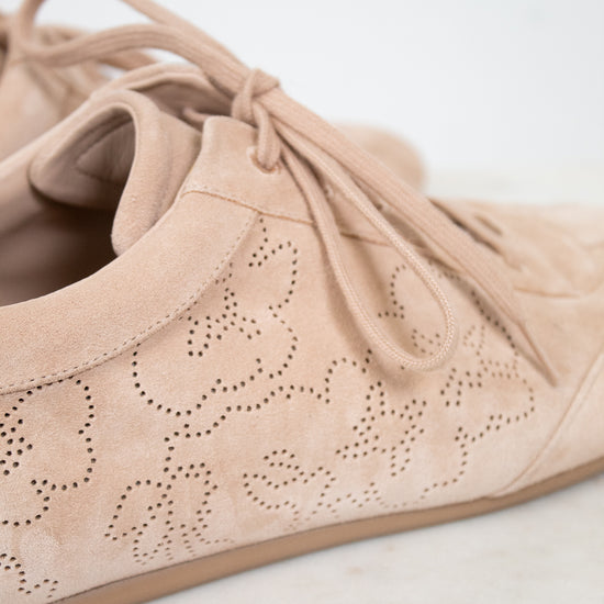 Beige suede shoe with decorative cut-out design on a light background