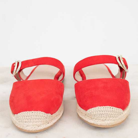 Pair of red espadrille sandals on a light wooden surface