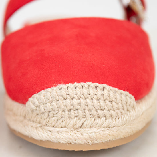 Red espadrille shoe with woven sole on a light background