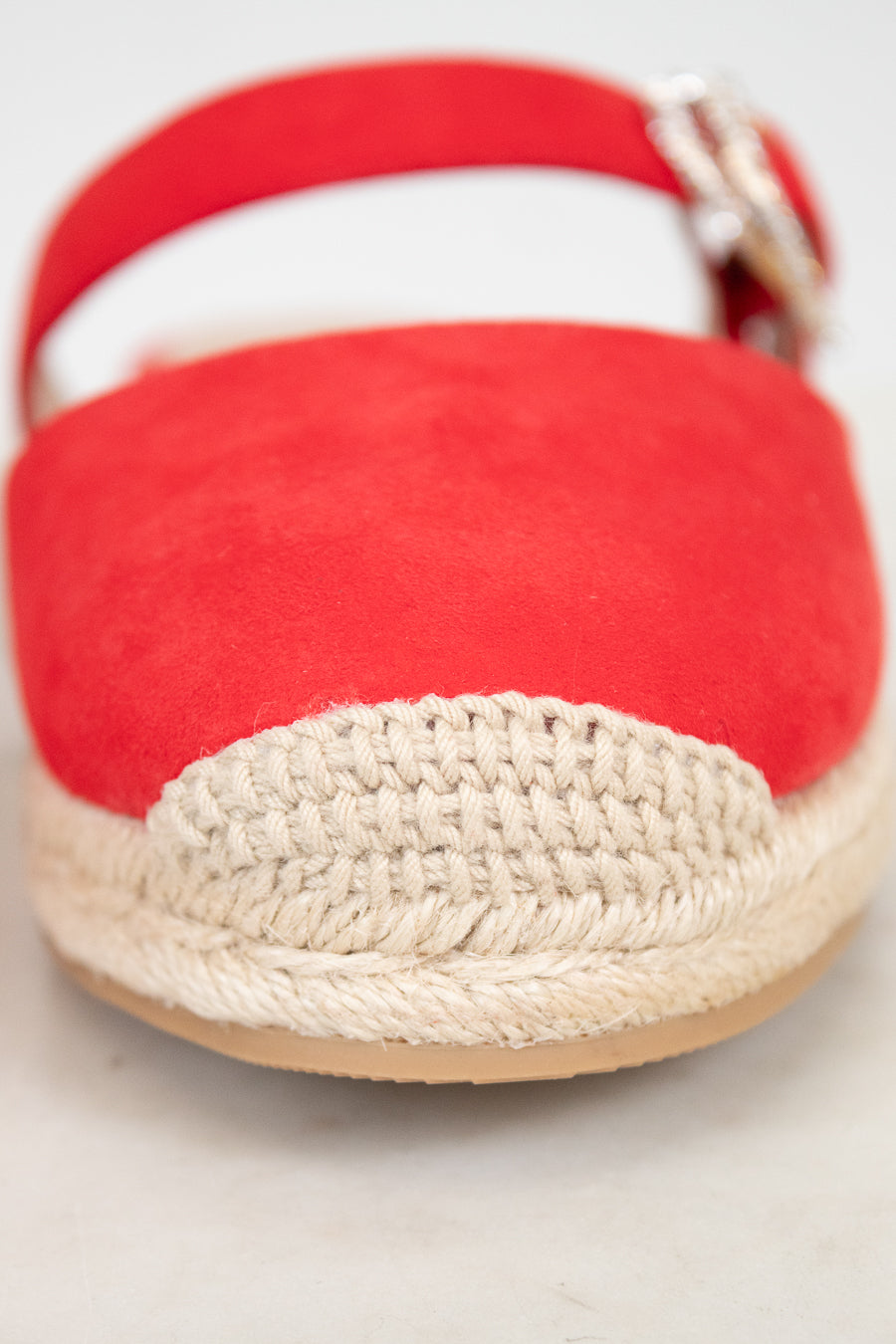 Red espadrille shoe with woven sole on a light background