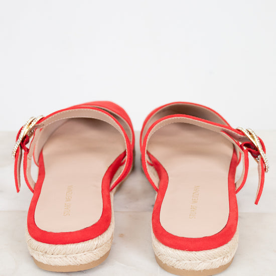 Red sandals with gold buckle on strap on a light gray background
