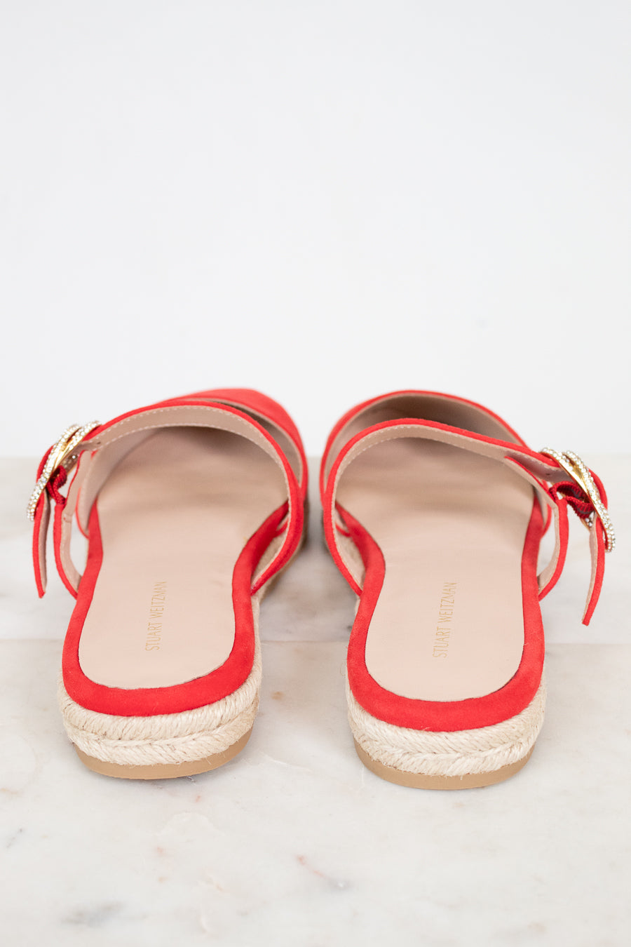 Red sandals with gold buckle on strap on a light gray background