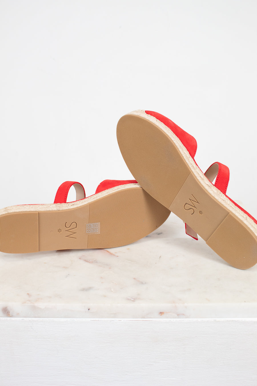 Red sandals with tan soles on a white background