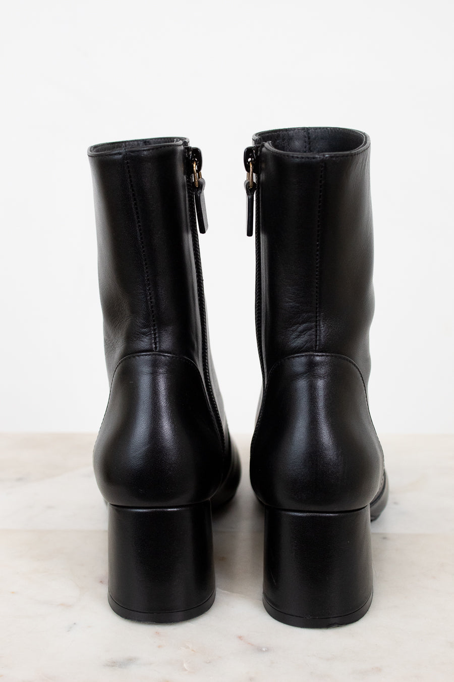 Pair of black leather boots on a marble surface