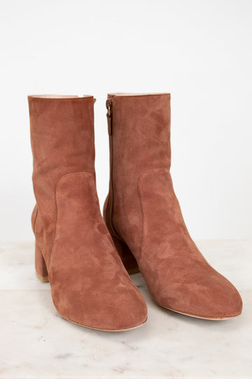 Pair of brown suede boots on a light gray background