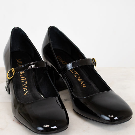Black patent shoes with gold buckle on a light background
