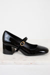 Black patent leather shoe with a gold buckle on a white background