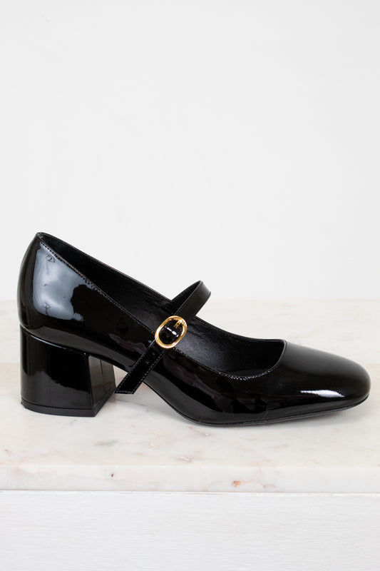 Black patent leather shoe with a gold buckle on a white background