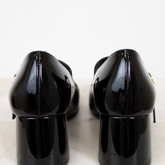 Back of black patent leather shoes on a light marble surface