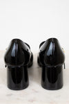 Back of black patent leather shoes on a light marble surface