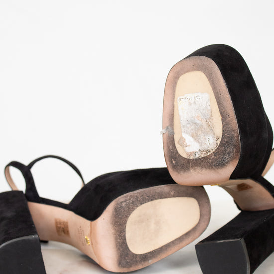 Black high-heeled shoes with beige soles on a white background