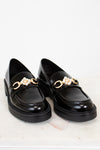 Black loafers with gold chain and pearl embellishments on a white background