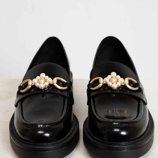 Black loafers with decorative elements on a light background
