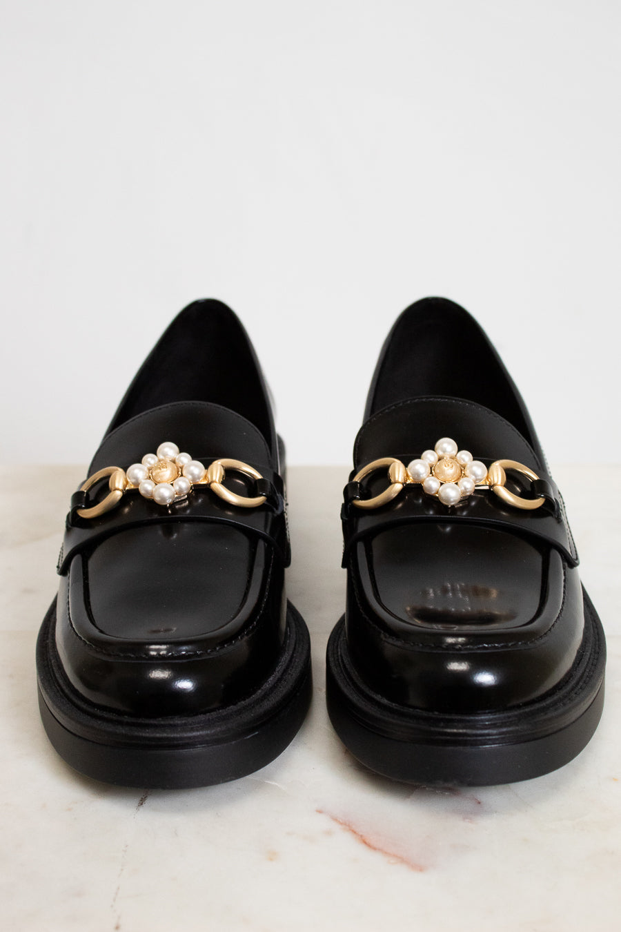 Black loafers with decorative elements on a light background