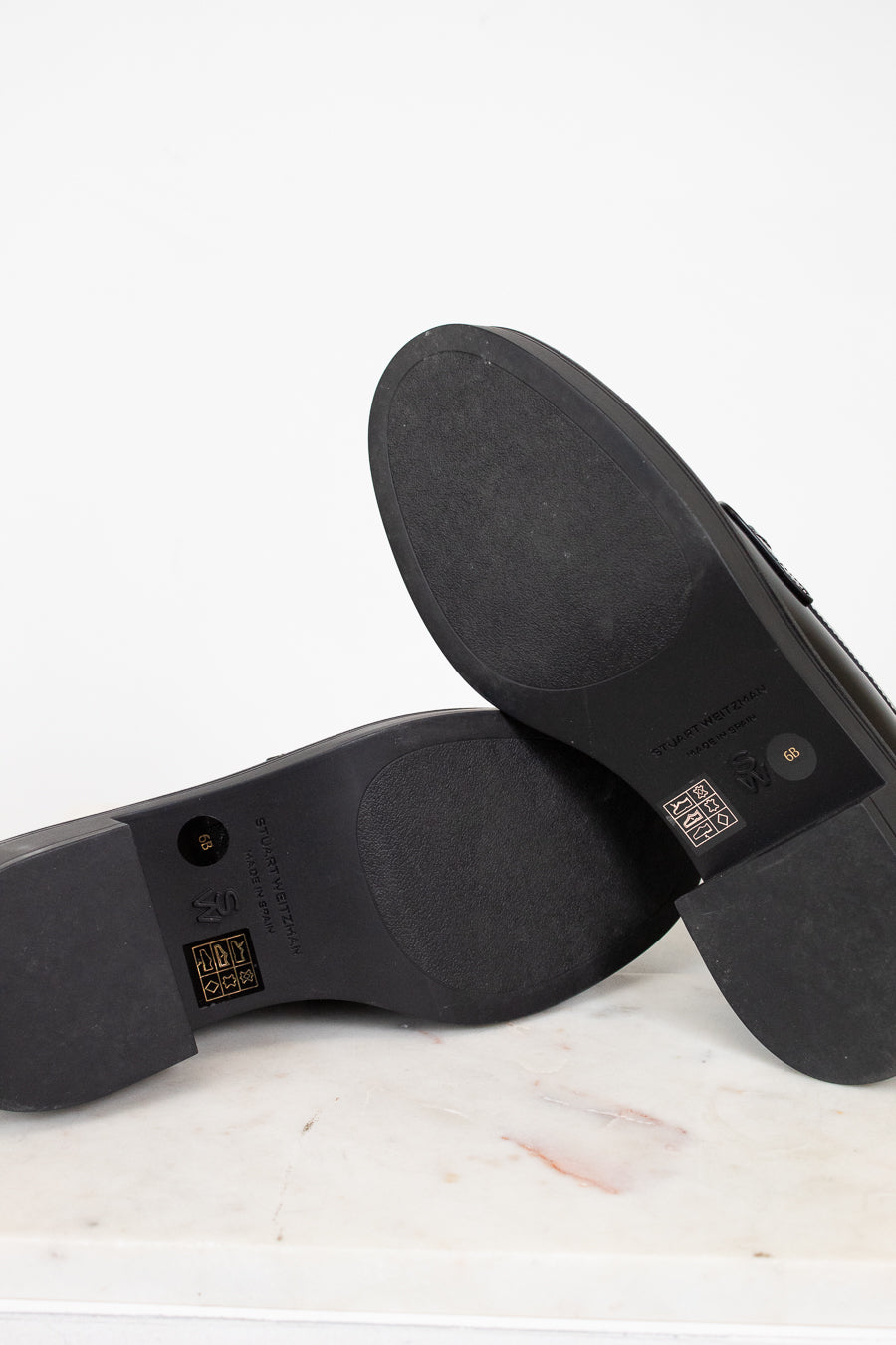 Close-up of black shoe soles with visible branding on a white background