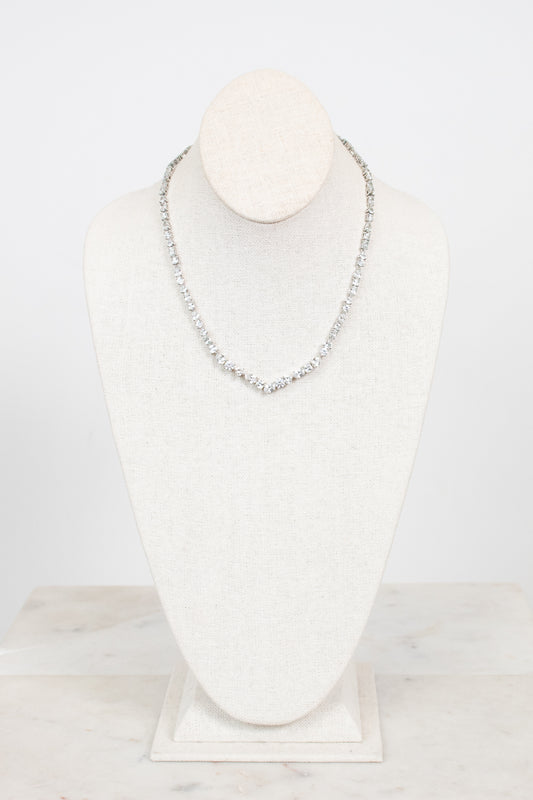 Multi-sized crystal necklace with pointed center detail displayed on a bust against a plain background