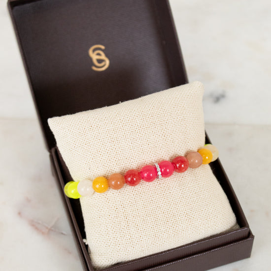 Colorful beaded bracelet in a brown box on a marble surface