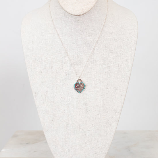 Dainty chain necklace with heart-shaped pendant on a white textured mannequin bust