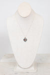 Dainty chain necklace with heart-shaped pendant on a white textured mannequin bust