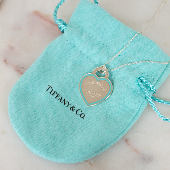 Tiffany & Co. necklace with heart tag on a turquoise pouch on a marble surface