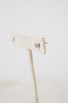 A side picture of TIFFANY & CO. silver diamond stud earrings placed on a beige earring holder and has a white background.