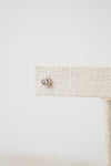 A close-up shot of one of the diamond studs, it is a circular shape with a diamond in the middle. The earring stud rest on a beige earring stand. 