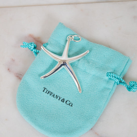 Silver starfish pendant on a Tiffany & Co pouch on a marble surface