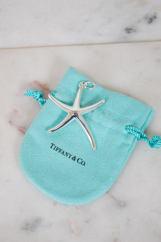 Silver starfish pendant on a Tiffany & Co pouch on a marble surface