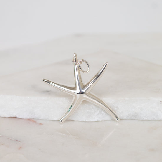 Silver starfish pendant on a marble surface