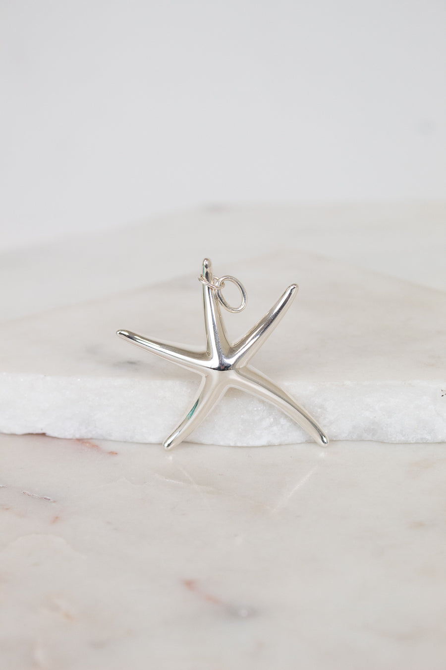 Silver starfish pendant on a marble surface