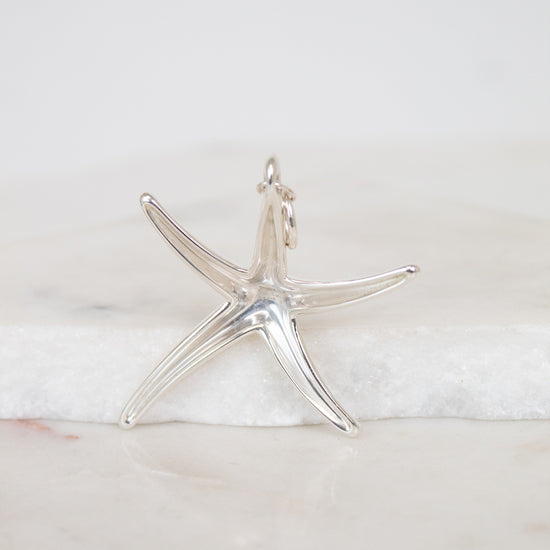 Silver starfish pendant on a marble surface