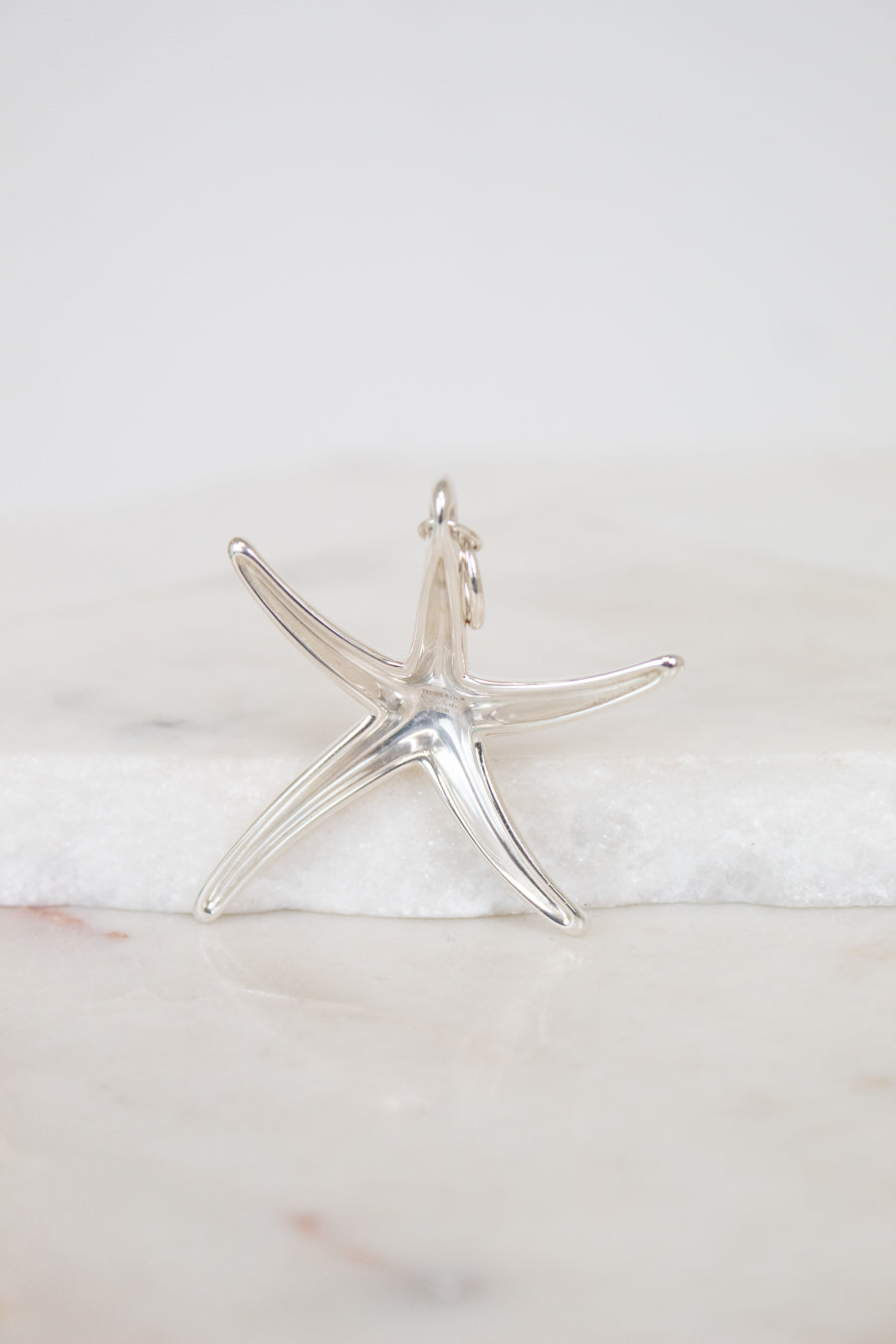 Silver starfish pendant on a marble surface