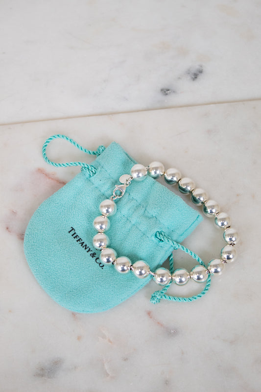 Silver beaded bracelet on a Tiffany & Co. branded pouch on a marble surface