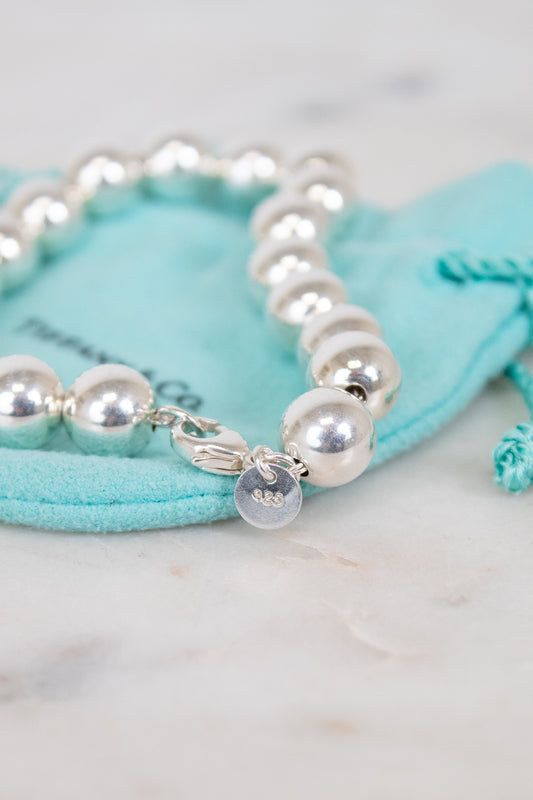 Silver bracelet with silver beads on a turquoise jewelry pouch