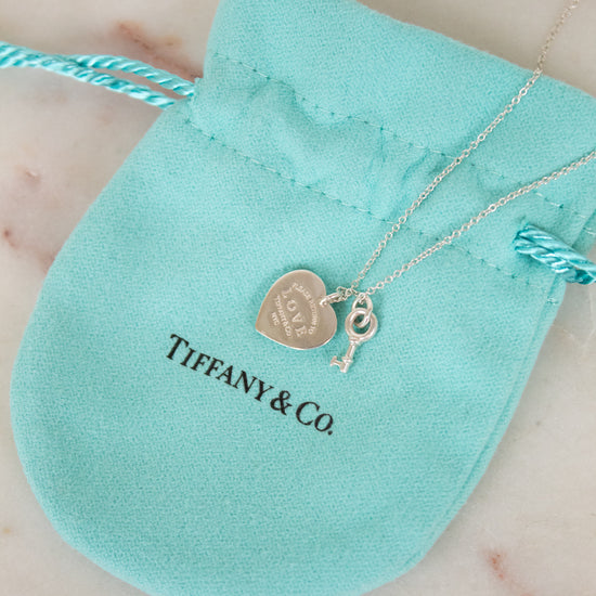 Tiffany & Co. necklace with heart and key charms on a turquoise pouch.