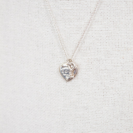 Silver heart-shaped pendant necklace on a light gray fabric background