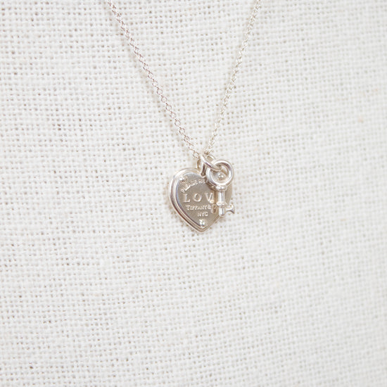 Silver necklace with a heart-shaped pendant on a light gray background