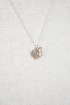 Silver necklace with a heart-shaped pendant on a light gray background