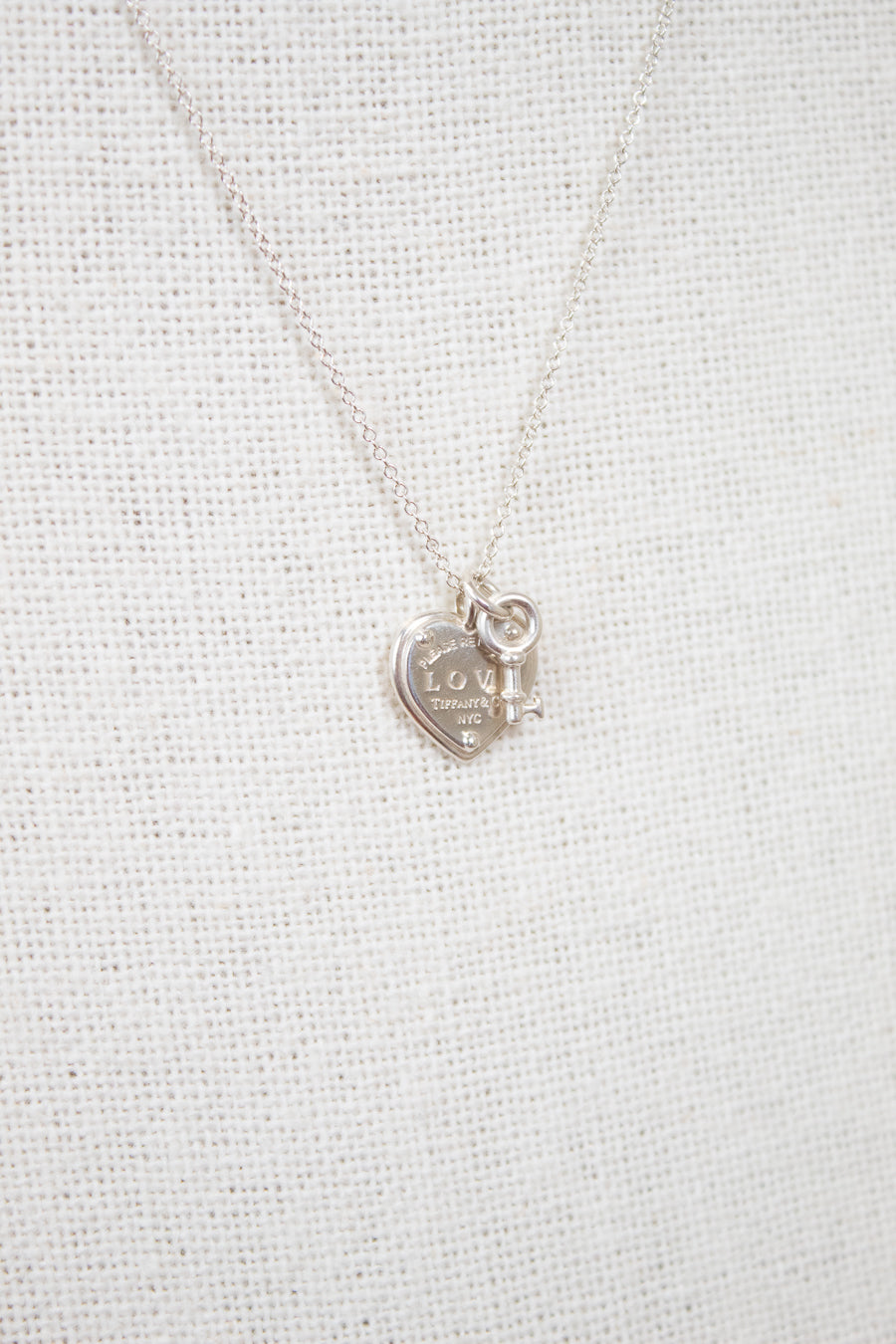 Silver necklace with a heart-shaped pendant on a light gray background