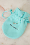 Tiffany & Co. infinity symbol necklace on a branded pouch on a marble surface
