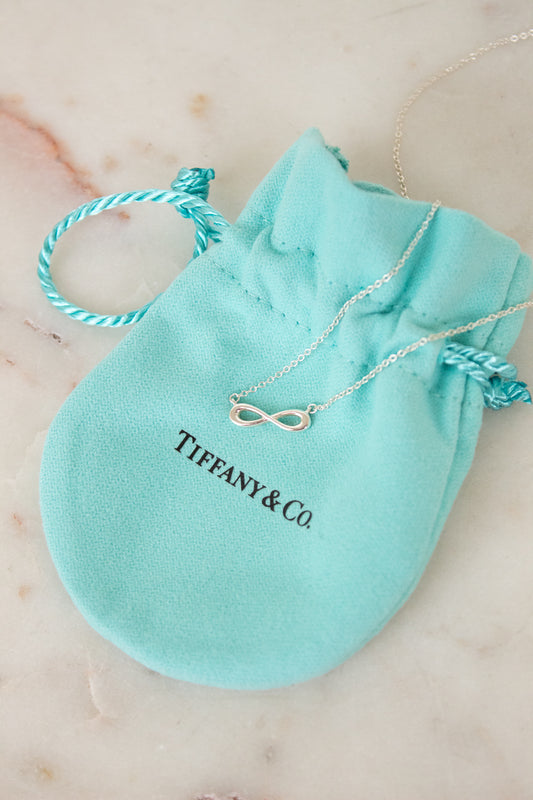 Tiffany & Co. infinity symbol necklace on a branded pouch on a marble surface