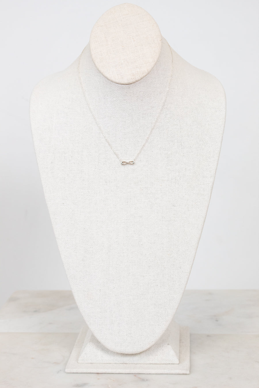 Infinity symbol necklace on white mannequin bust