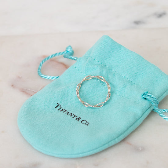Silver ring on a Tiffany & Co. branded turquoise pouch on a marble surface