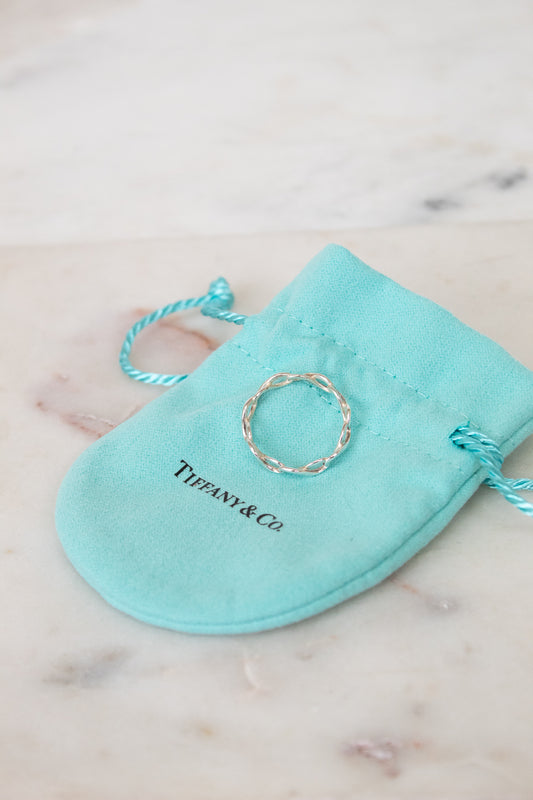 Silver ring on a Tiffany & Co. branded turquoise pouch on a marble surface