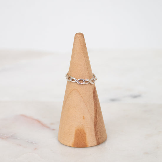 Silver ring on a wooden cone with a white background