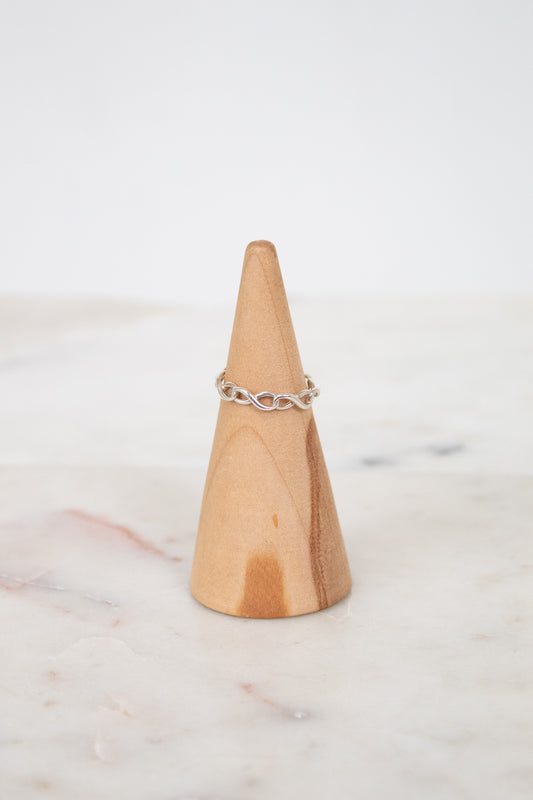 Silver ring on a wooden cone with a white background