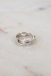Two interlocking silver rings with engraved text on a marble surface