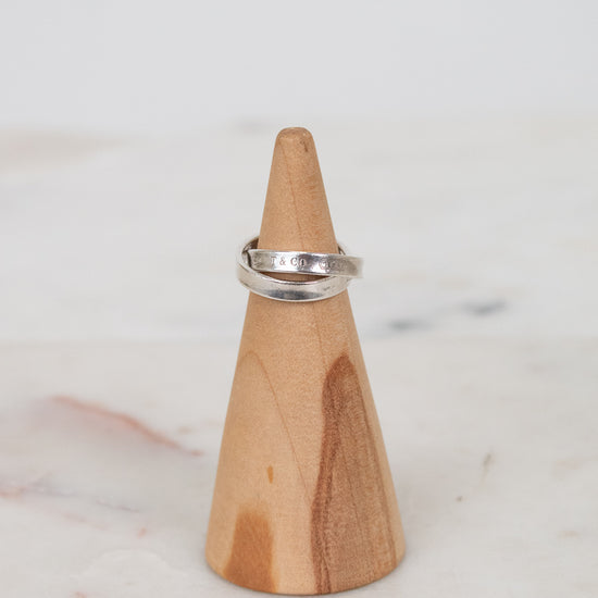 Silver ring on a wooden ring stand against a marble background