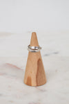 Silver ring on a wooden ring stand against a marble background